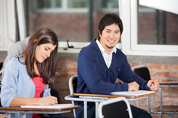 Image showing Student Sitting At Desk With Classmate In Classroom