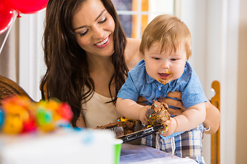 Image showing Mother Holding Baby Boy Eating Cupcake