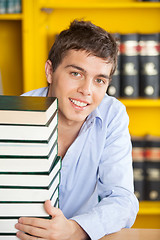 Image showing Student With Stacked Books Smiling At Table In Library