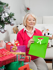 Image showing Woman Holding Bag While Sitting By Christmas Presents