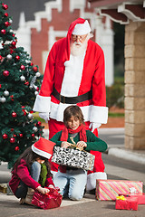 Image showing Santa Claus Looking At Children Opening Christmas Presents