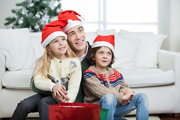 Image showing Father And Siblings Wearing Santa Hats During Christmas