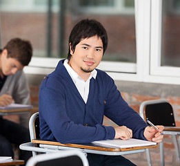 Image showing Confident Student Sitting At Desk In Classroom