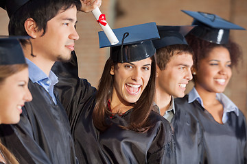 Image showing Student Holding Certificate While Standing With Friends At Colle