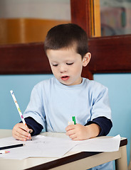 Image showing Boy With Pencil Drawing On Paper In Classroom