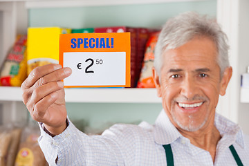 Image showing Happy Male Owner Showing Discount Sign In Store