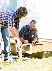 Image showing Workers Measuring Wood At Construction Site