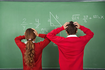 Image showing Confused Schoolchildren Standing Against Board