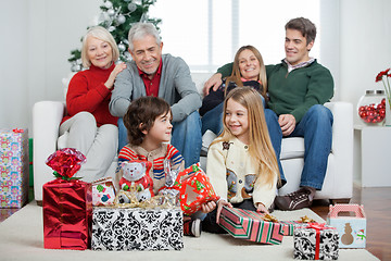 Image showing Children With Christmas Presents While Family Sitting On Sofa