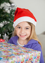 Image showing Smiling Girl In Santa Hat Holding Christmas Gift