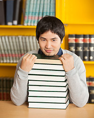 Image showing Confident Man With Stacked Books Sitting In University Library