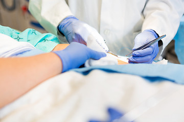 Image showing Doctor Stitching Patient's Wound While Nurse Assisting Him
