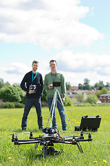 Image showing Technicians Holding Remote Controls Of UAV Helicopter