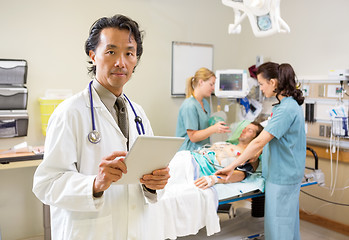 Image showing Doctor Holding Digital Tablet While Nurses Treating Male Patient
