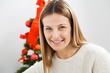 Image showing Smiling Woman Against Christmas Tree