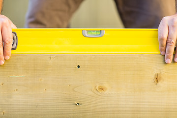 Image showing Worker Holding Spirit Level On Wood Outdoors