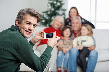 Image showing Father Photographing Family Through Mobilephone During Christmas