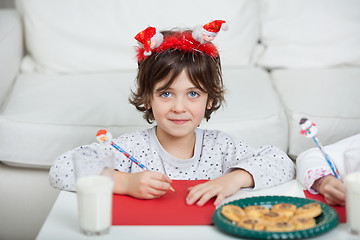 Image showing Boy Wearing Santa Headband Writing Letter At Home