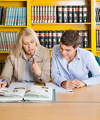 Image showing Teacher And Student Looking At Book While Sitting In Library