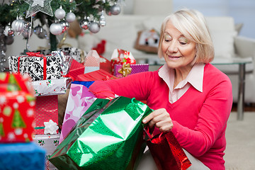 Image showing Woman Looking In Bag While Sitting By Christmas Presents