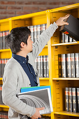 Image showing Student Taking Book From Shelf In University Library