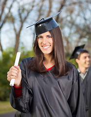 Image showing Woman In Graduation Gown Holding Diploma On College Campus
