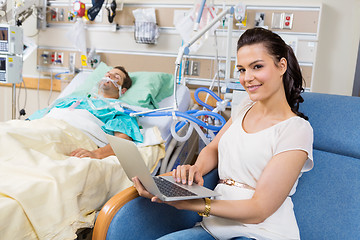 Image showing Woman With Laptop Sitting By Male Patient In Hospital