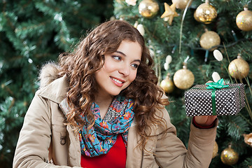 Image showing Woman Looking At Present Against Christmas Tree