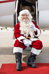 Image showing Santa Holding Milk Glass While Sitting On Private Jet's Ladder