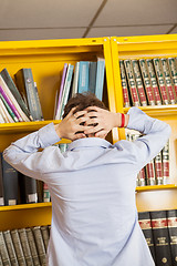 Image showing Frustrated Man Standing Against Bookshelf In Library