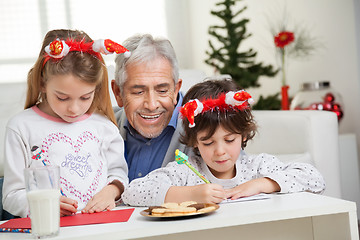 Image showing Man Looking At Children Making Christmas Greeting Card