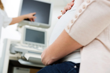 Image showing Pregnant Woman With Doctor Pointing At Ultrasound Scan