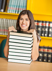Image showing Confident Student Sitting With Stacked Books In Library