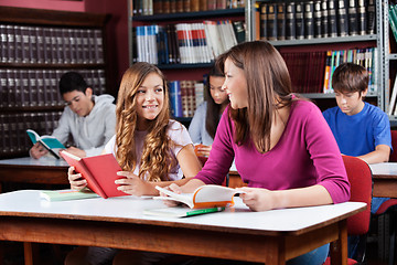 Image showing Female Friends Looking At Each Other While Sitting In Library