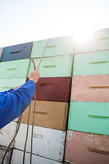 Image showing Beekeeper Tying Rope On Stacked Honeycomb Crates