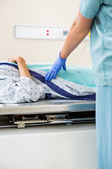 Image showing Nurse Standing By Patient Lying On Xray Table