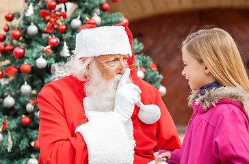 Image showing Santa Claus Gesturing Finger On Lips While Looking At Girl