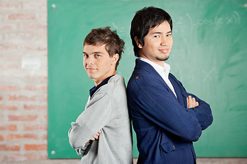 Image showing Students Standing Arms Crossed Against Greenboard In Classroom