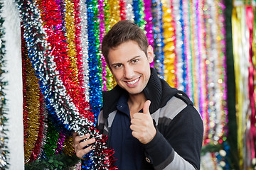 Image showing Man Gesturing Thumbs Up While Holding Tinsels At Store