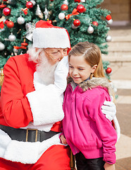 Image showing Santa Claus Whispering In Girl's Ear Against Christmas Tree