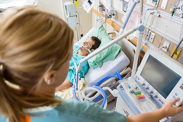 Image showing Nurse Pressing Monitor's Button With Patient Lying On Bed