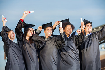 Image showing Students Holding Certificates Against Sky