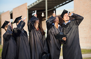 Image showing Students In Graduation Gown Looking Through Certificates On Camp