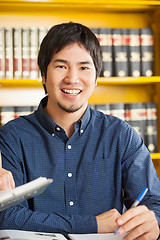 Image showing Male Student Sitting Against Bookshelf In University Library