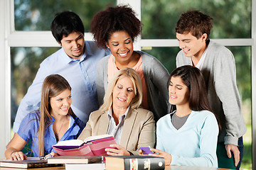 Image showing Professor And Students Discussing Over Book In Classroom