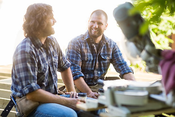 Image showing Workers Holding Disposable Coffee Cups While Sitting On Frame