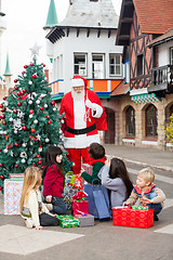 Image showing Children With Gifts Looking At Santa Claus