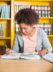 Image showing Student Writing In Book At Library