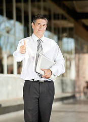 Image showing Confident Teacher With Books Gesturing Thumbsup On Campus