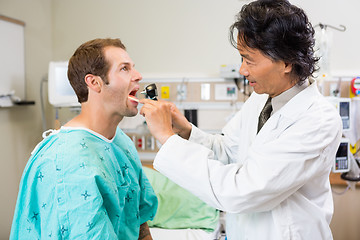 Image showing Doctor With Depressor And Otoscope Checking Patient's Mouth